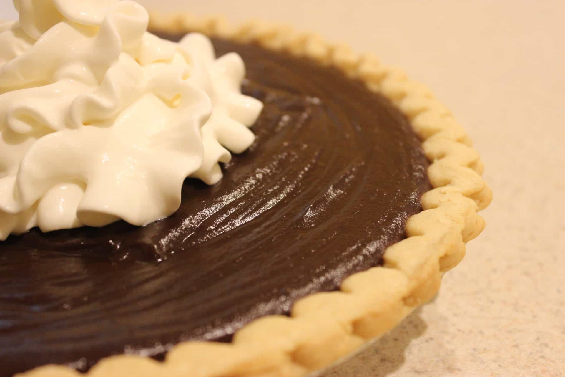 Up close shot of a chocolate pie with whipped cream.