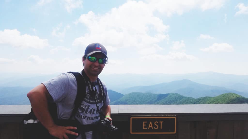 Brett standing with the "East" sign at the top of Brasstown Bald.